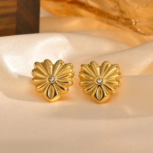 Boucles d'oreilles cœur dorées avec texture radiale et zircon sur soie blanche