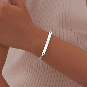 Close-up of polished silver stainless steel ID bar pearl chain bracelet on wrist