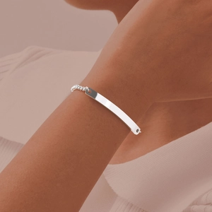 Close-up of a silver curved bar pearl chain bracelet worn on a woman's wrist