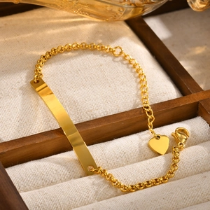Detailed shot of gold-plated stainless steel bar bracelet with heart charm on tray