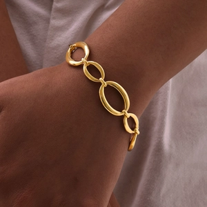 Détail d'un bracelet doré à grands maillons ovales porté pour un look moderne chic
