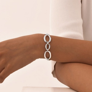 Gros plan d'un bracelet gourmette en acier argenté poli porté par un mannequin