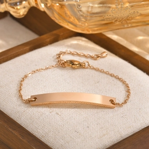 Detail of rose gold stainless steel ID bar bracelet with lobster clasp on white cushion