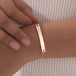 Detail of rose gold minimalist bar bracelet with polished finish worn on wrist
