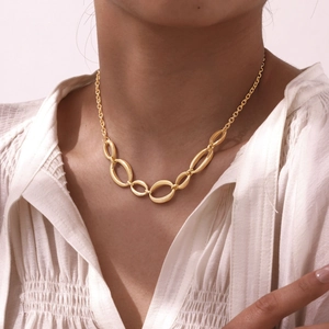 Gros plan d'un collier à grosses mailles géométriques dorées sur le cou