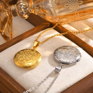 Detalle de relicarios redondos de acero grabados en oro y plata sobre bandeja de madera