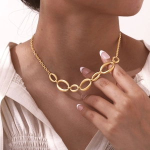 Gros plan d'un bracelet gourmette en acier inoxydable doré porté au poignet