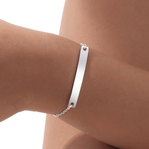 Macro detail of silver curved bar bracelet on wrist showing polished metallic finish