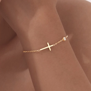 Nahaufnahme des goldenen Kreuzarmbands mit weißem Zirkon für einen minimalistischen Stil