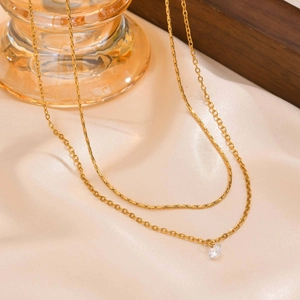 Double layer gold necklace with white zircon pendant on elegant satin background
