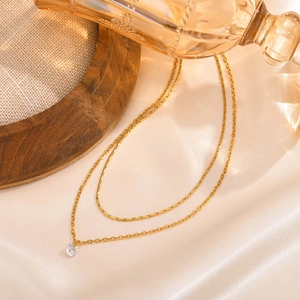 Detail of layered gold stainless steel necklace with round cubic zirconia pendant