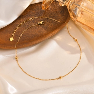 Collier en acier inoxydable doré avec trois perles facettées et un petit pendentif cœur