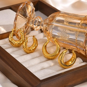 Macro shot of two pairs of gold thick hoops with spiral texture in a jewelry box