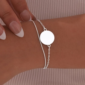 Macro detail of silver double-layer stainless steel chain bracelet with blank round pendant