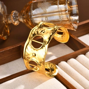 Nahaufnahme einer goldfarbenen Armspange mit Hammerschlag-Optik und geometrischen Ringen