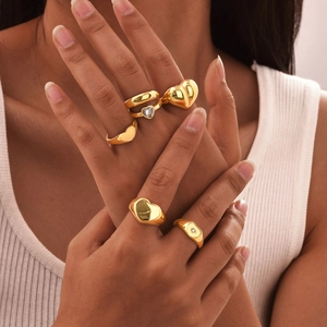 Set aus goldenen Edelstahlringen mit Herz-Motiv und Zirkonia-Steinen an weiblicher Hand