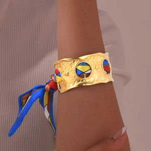 Details des goldfarbenen Hammerschlag-Armreifs mit buntem Seidenschal im Vintage-Stil