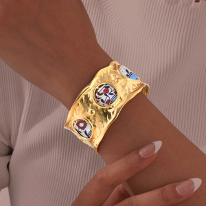 Details eines goldenen breiten Armreifs mit feinen Vogel- und Blumenmustern Einlagen