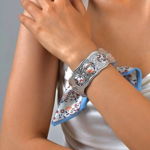 Details von silbernem wellenförmigem Armreif mit blauem Blumenschal-Akzent am Handgelenk