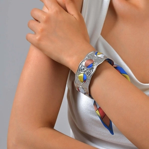 Close-up of hammered silver cuff bracelet with colorful geometric silk scarf detail