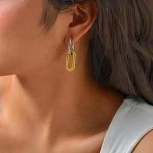 Close-up of dual-tone U-shaped earrings with silver top and gold textured bottom ring