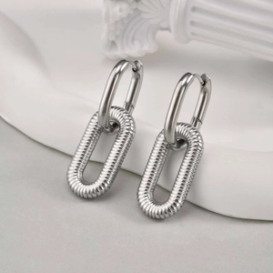 Detail view of silver double-hoop earrings with spiral texture on a luxury white background