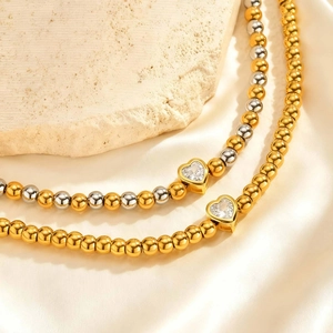 Macro-opname van gouden kralenarmband met sterlogo's en een hartvormige zirkoon