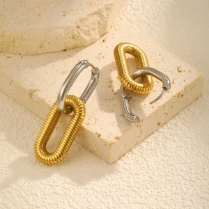 Detailed macro view of interlocking gold textured and silver polished oval hoop earrings