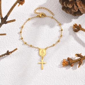 Détail du bracelet en acier doré à perles avec médaille de la Vierge Marie et croix