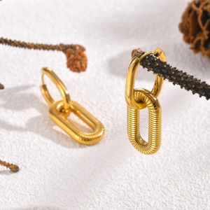 Detail of gold U-shaped double hoop earrings with textured thread pattern on a dry branch