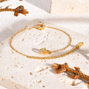 Detail of K18 engraved tag and zircon sunflower pendant on gold stainless steel bracelet