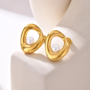 Orecchini geometrici dorati con perla bianca su un espositore in stile minimal