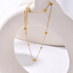 Collana in acciaio inossidabile dorato con perline e catena regolabile su fondo bianco