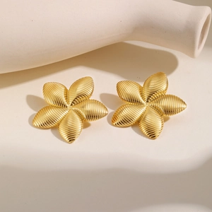 Gros plan de boucles d'oreilles fleurs dorées aux pétales texturés en spirale