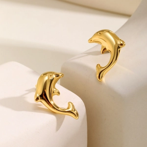 Polished golden dolphin stud earrings for women on a minimalist geometric jewelry stand