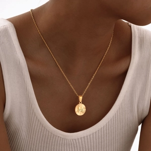 Collana in acciaio dorato con ciondolo rotondo a raggiera e lettera M a rilievo