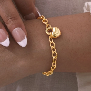 Dettaglio di un bracciale in acciaio inossidabile dorato con ciondolo a lucchetto a cuore