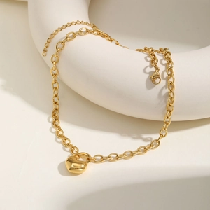 Détail du bracelet chaîne à maillons dorés en acier inoxydable avec pendentif cœur poli