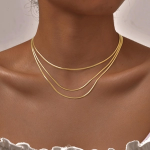 Détail d'un collier à trois couches en maille serpent dorée sur un mannequin