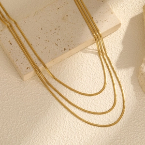 Collier triple chaîne serpent en acier inoxydable doré pour femme sur fond de pierre