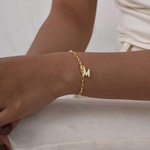 Detailopname van een vergulde armband met een sprankelende letter M-bedel bezet met zirkoon