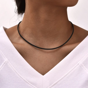 Primo piano di un girocollo minimalista in corda nera indossato con un top bianco