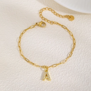 Detail van een 18K gouden letter A hanger met zirkonia aan een fijne schakelketting