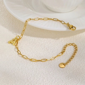 Detail van gouden paperclip armband met glinsterende hanger met letter A en zirkoon
