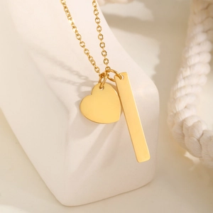 Detailed macro view of gold-plated bar and heart charms on a minimalist stainless steel chain