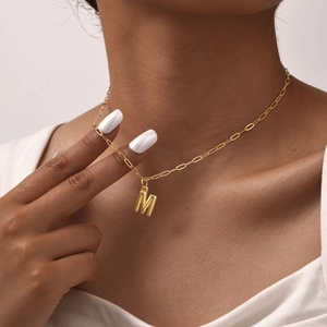 Gros plan d'un pendentif lettre M 3D doré sur un collier chaîne trombone pour femme