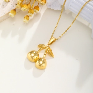 Collier avec pendentif cerise en acier inoxydable doré poli sur un élégant socle blanc
