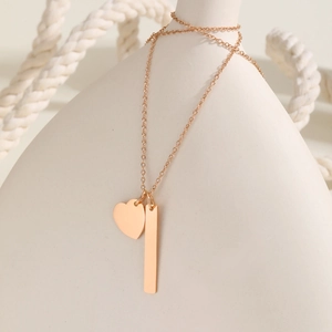Detailed shot of rose gold heart and vertical bar pendants on a minimalist chain