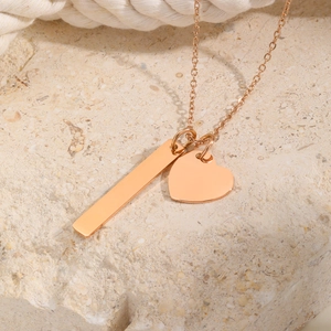Macro view of a blank rose gold vertical bar and heart pendant for DIY engraving