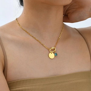Close-up of a gold oval pendant necklace with a blue gemstone and crystal charms